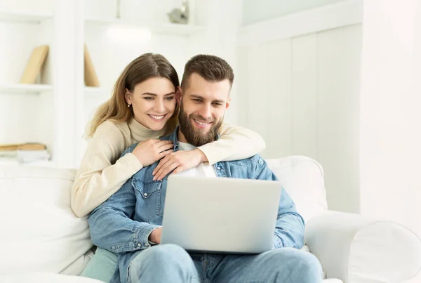 Молодая пара проводит время дома, мужчина с ноутбуком — стоковое фото