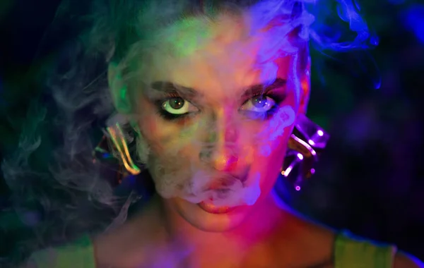 Sexy girl smoking e-cigarette in colourful neon lights — Stock Photo, Image