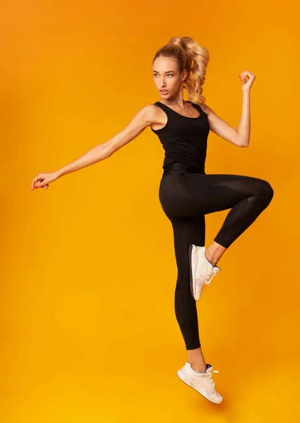 Fit vrouw oefenen Jumping in Studio over geel — Stockfoto