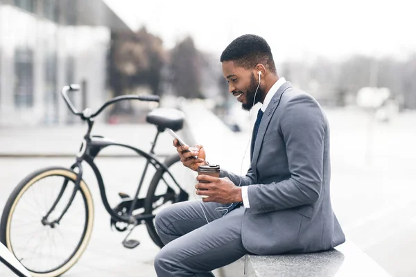 Bonito empresário afro mensagens de texto no telefone durante o coffee break — Fotografia de Stock