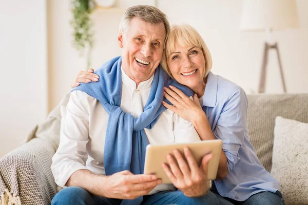 Casal sênior feliz com tablet digital sorrindo para a câmera — Fotografia de Stock