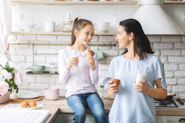 Mädchen und ihre Mutter essen Cupcakes und trinken gemeinsam Milch — Stockfoto