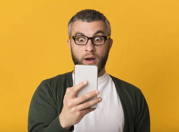 Surpreendido bonito homem olhando para o celular com os olhos bem abertos — Fotografia de Stock