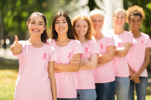 Voluntários de câncer de mama em pé na linha Gesturing Thumbs-Up no parque — Fotografia de Stock