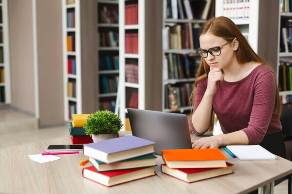 Серьёзная студентка читает научную статью онлайн
