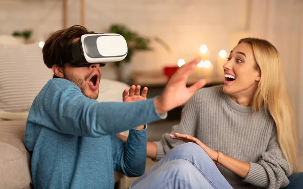 Casal animado usando fone de ouvido de realidade virtual em casa — Fotografia de Stock