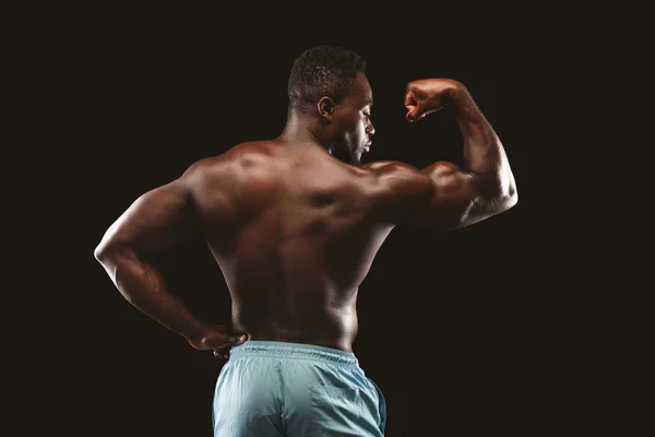 Hot bodybuilder demonstrating his biceps over black background — Stock Photo, Image