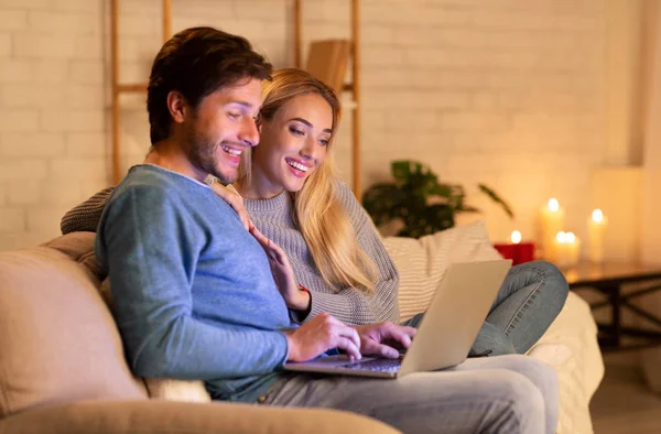 Pareja viendo la película en el ordenador portátil sentado en el sofá en casa —  Fotos de Stock