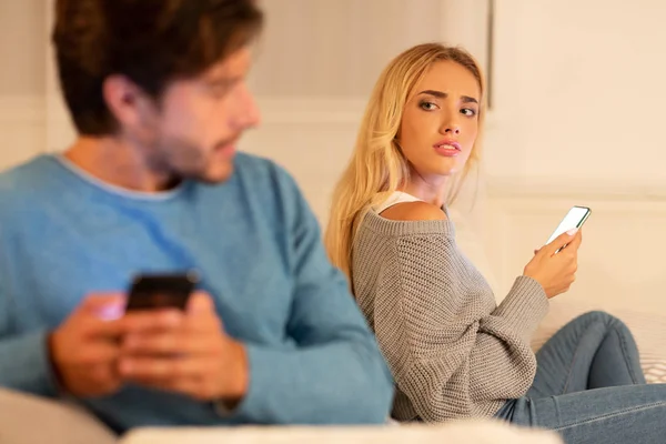 Husband Texting On Cellphone Sitting With Suspicious Wife At Home — Stock Photo, Image