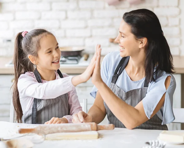 Menina bonito e sua mãe dando alta cinco na cozinha — Fotografia de Stock