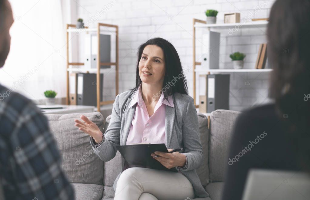 Confident psychologist talking with patients in her consulting room