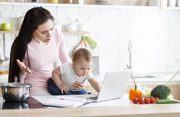 Mère choquée regardant son bébé en cliquant sur un ordinateur portable — Photo