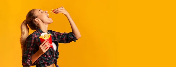 Ragazza allegra mangiare patate fritte francesi su sfondo giallo, Panorama — Foto Stock