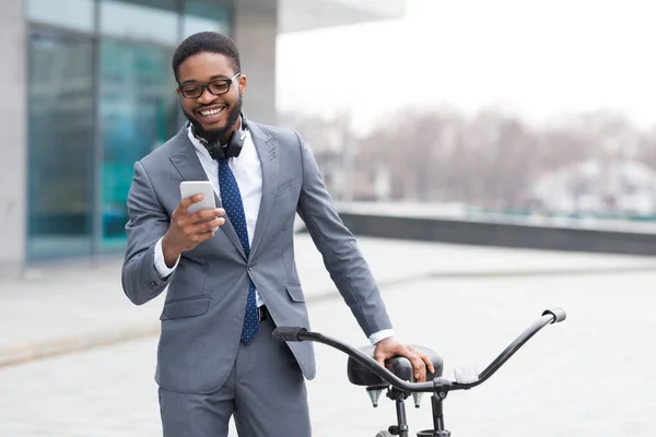 Empreendedor feliz mensagens de texto no telefone perto de bicicleta — Fotografia de Stock