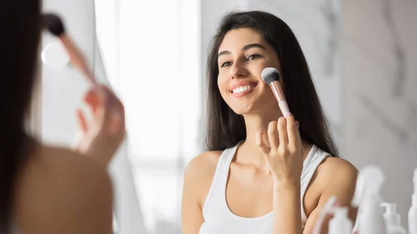 Girl Applying Face Powder Using Makeup Brush Standing In Bathroom
