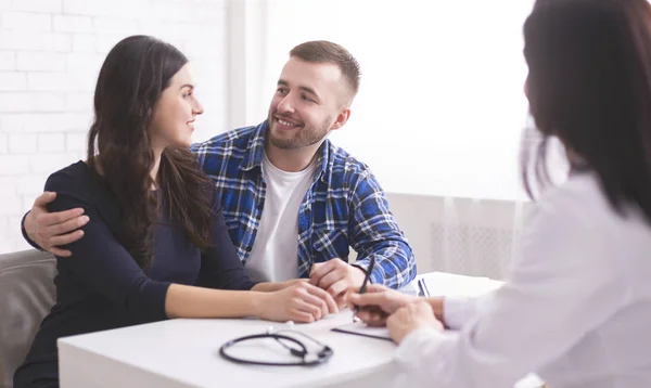 Pareja joven sonriendo el uno al otro, feliz de escuchar noticias de los médicos — Foto de Stock