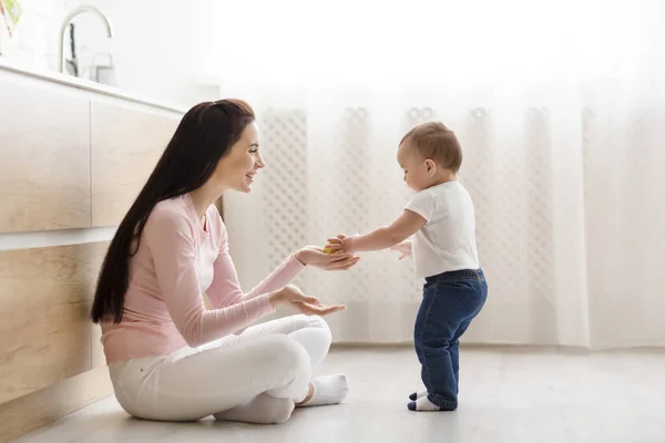 Vriendelijke baby delen appel met mama, samen spelen in de keuken — Stockfoto