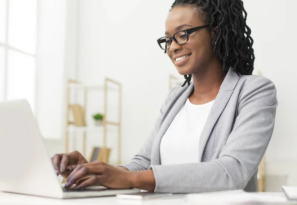 Sorrindo gerente de escritório trabalhando no laptop sentado no local de trabalho — Fotografia de Stock