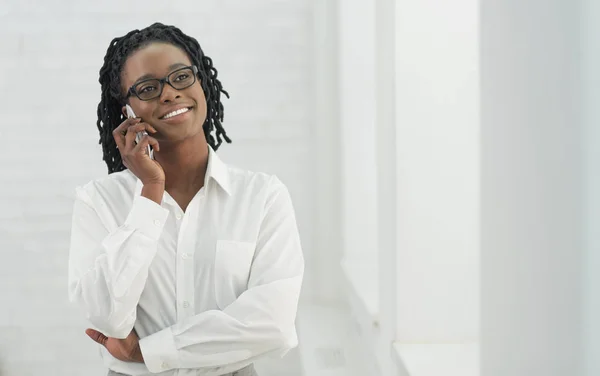 Улыбающаяся афроамериканка разговаривает по телефону в помещении — стоковое фото