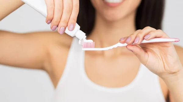 歯ブラシ、白い背景、パノラマに歯磨き粉を置く認識できない女性 — ストック写真