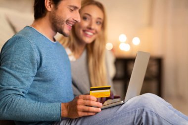 Genç Çift Evde Dizüstü Bilgisayar ve Kredi Kartı kullanarak online alışveriş