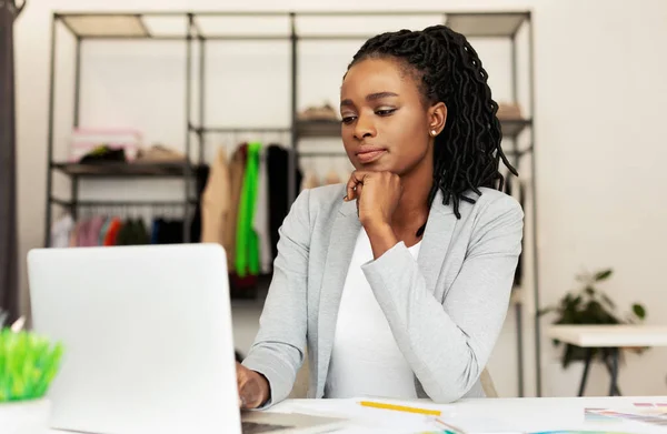 Young Afro Businesswoman Using Laptop In Clothing Store