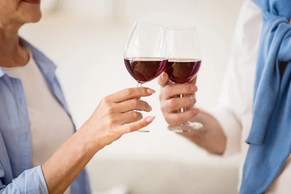 Maduro casal clinking copos com vinho tinto em casa — Fotografia de Stock