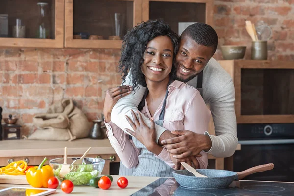 Agradecido hombre africano abrazando a su esposa mientras cocina en la cocina — Foto de Stock
