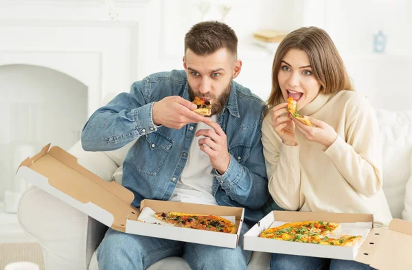 Young couple enjoying eating pizza and watching tv at home — Stock Photo, Image