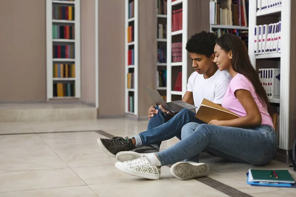 Pareja joven de estudiantes negros estudiando en el piso de la biblioteca — Foto de Stock
