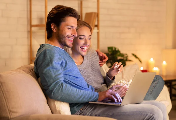 집에서 휴식을 취하는 팝콘을 먹는 영화를 보는 노트북을 사용하는 배우자 — 스톡 사진