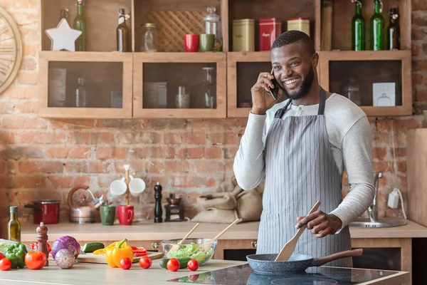 Młody czarny człowiek rozmowy na telefon komórkowy w kuchni — Zdjęcie stockowe