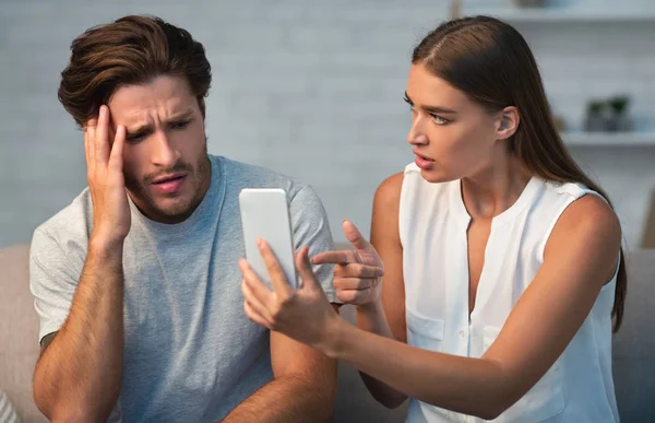 Femme montrant la tricherie mari téléphone cellulaire exigeant explication à la maison — Photo