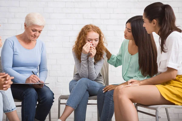 Разнообразные женщины, поддерживающие плачущую девочку во время групповой психотерапии в помещении — стоковое фото