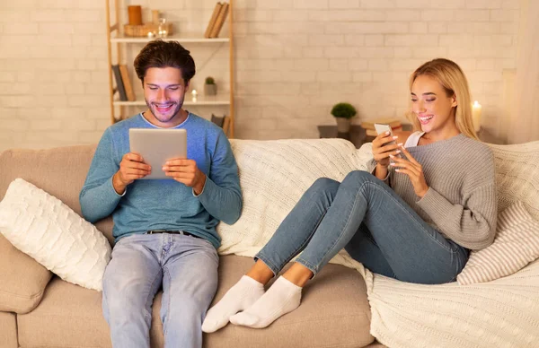 Χαμογελαστός άνθρωπος και γυναίκα χρησιμοποιώντας tablet και smartphone στο σπίτι — Φωτογραφία Αρχείου