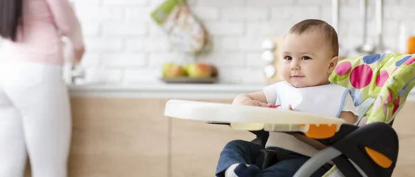 Симпатичный ребенок, сидящий в детском стульчике на кухне — стоковое фото