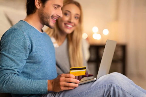Casal jovem compras on-line usando laptop e cartão de crédito em casa — Fotografia de Stock