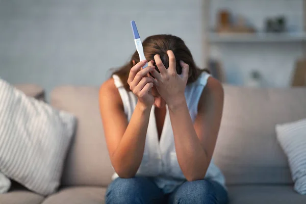 Irriconoscibile depresso ragazza holding gravidanza test seduta su divano coperta — Foto Stock