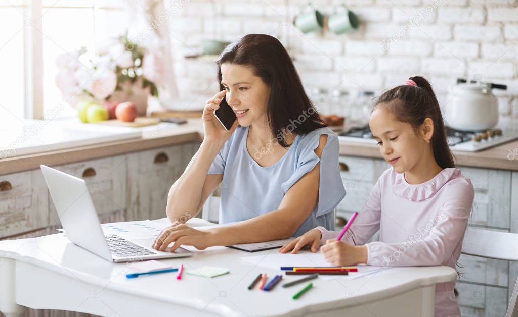 Young woman working at home and spending time with daughter