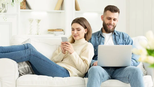 Couple at home. Man with laptop, woman with phone — Stock Photo, Image