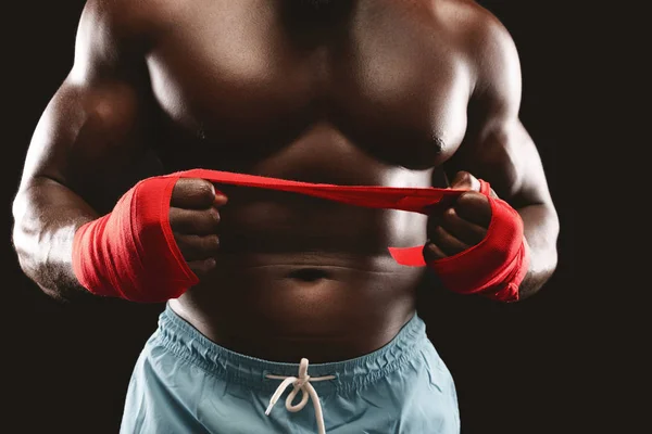 Boxeador profesional tirando de vendaje deportivo rojo sobre fondo negro — Foto de Stock