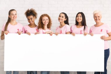 Tuğla Duvar üzerinde beyaz tahta tutan pembe t-shirt Kadınlar