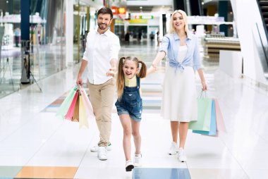 Alışveriş merkezinde alışveriş yapan üç kişilik aile