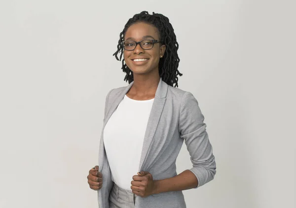 Negro mujer de negocios sonriendo en la cámara de pie sobre fondo gris —  Fotos de Stock