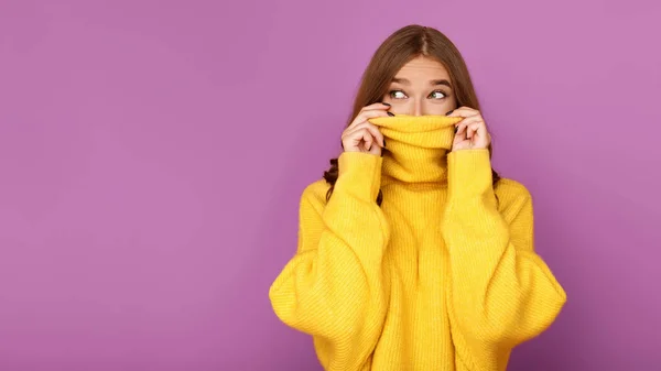 Millennial kvinna tittar ut från tröja, lila bakgrund — Stockfoto