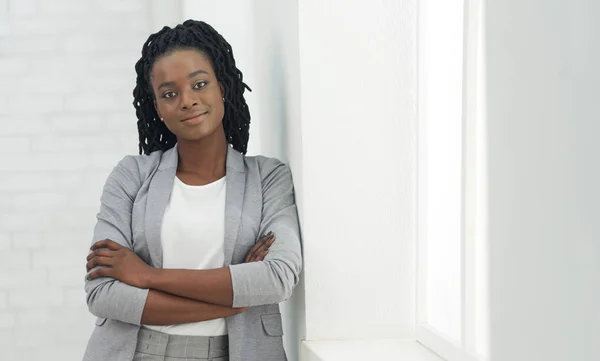 Молодая черная леди смотрит в камеру, стоящую в офисе — стоковое фото