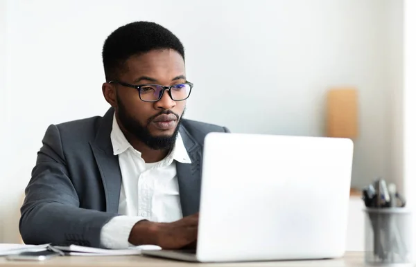 Homme d'affaires noir sérieux travaillant sur ordinateur portable dans le bureau — Photo