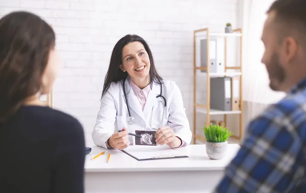 Amistoso médico que explica el diagnóstico de embarazo a la pareja joven — Foto de Stock