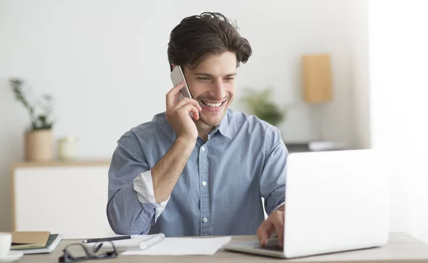 Щасливий підприємець говорить на мобільному телефоні сидячи в ноутбуці в офісі — стокове фото