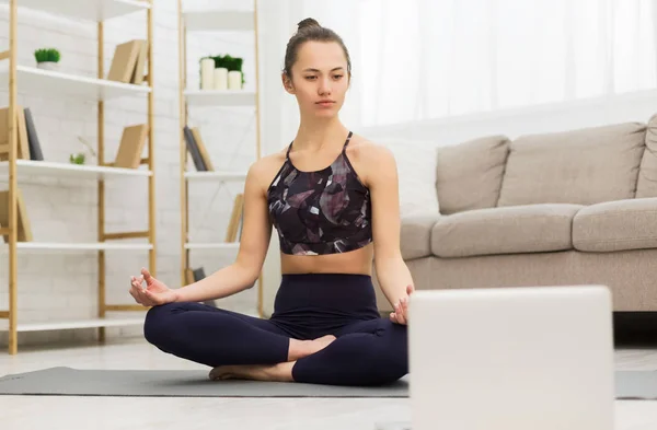 Online training. Girl sitting in lotus position with laptop